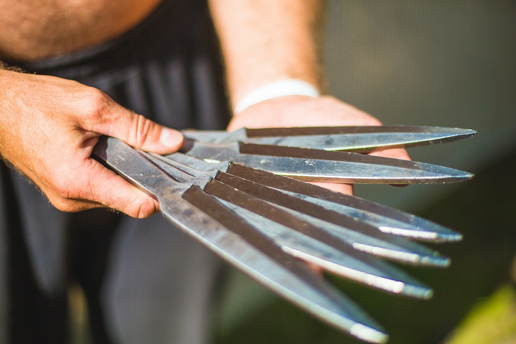 A man holds and demonstrates throwing knives. Knife throwing training.