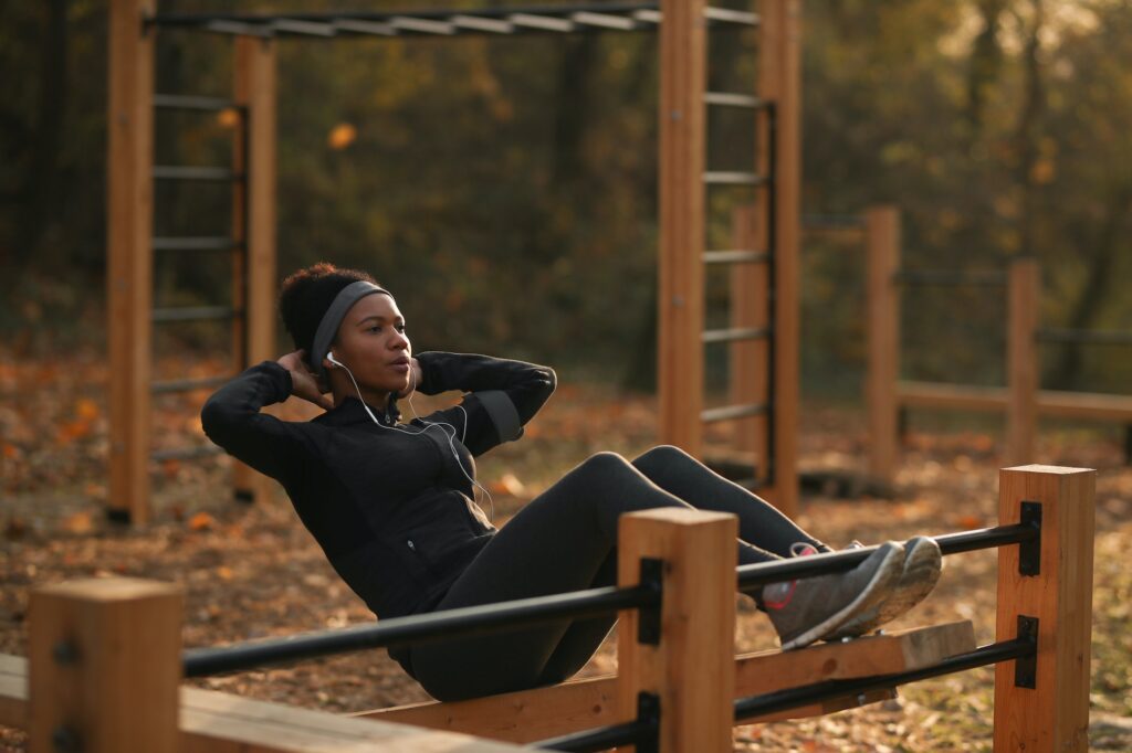 African American female athlete doing sit-ups at outdoor gym.