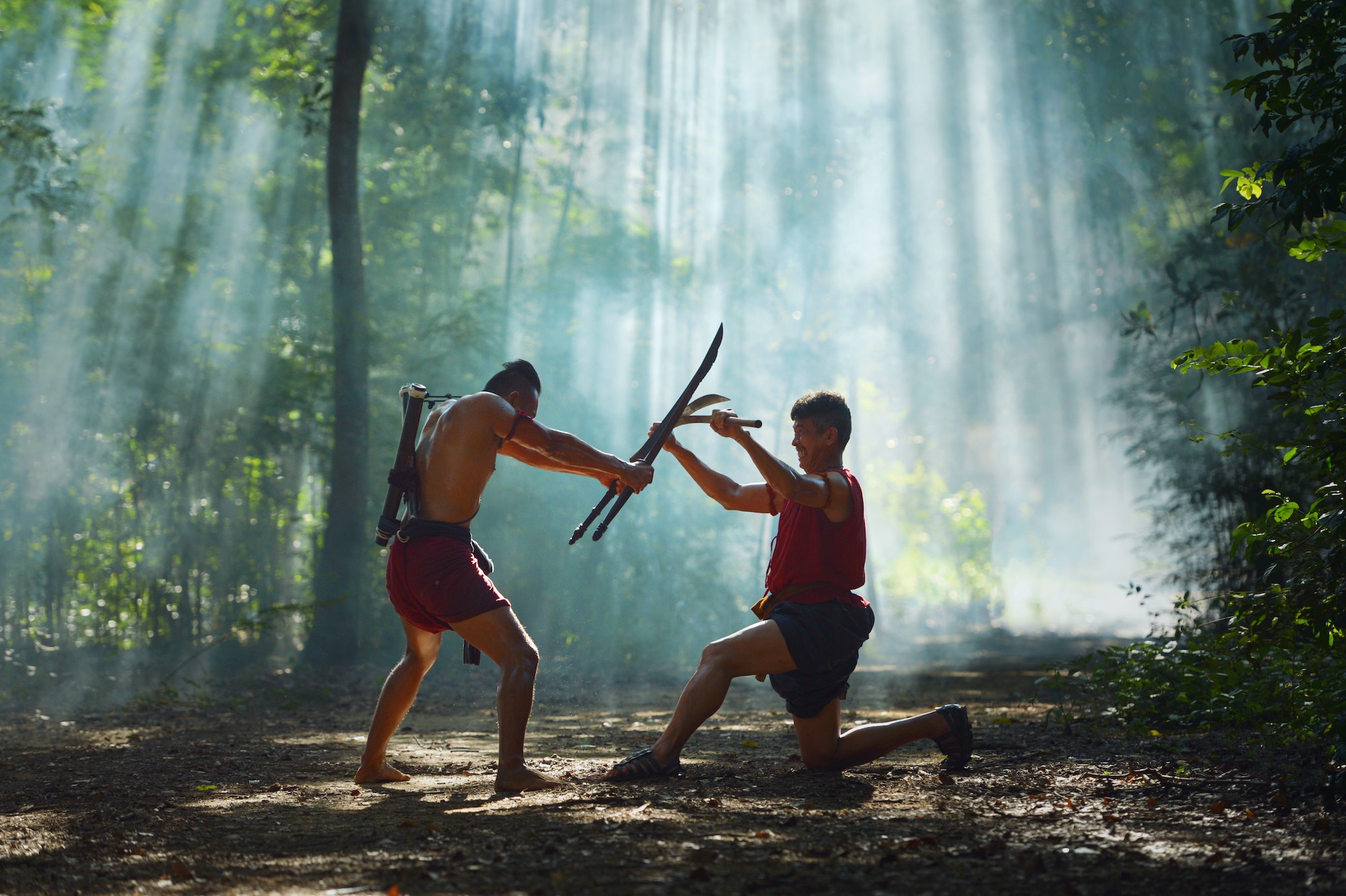Two men fighting with sticks in the woods