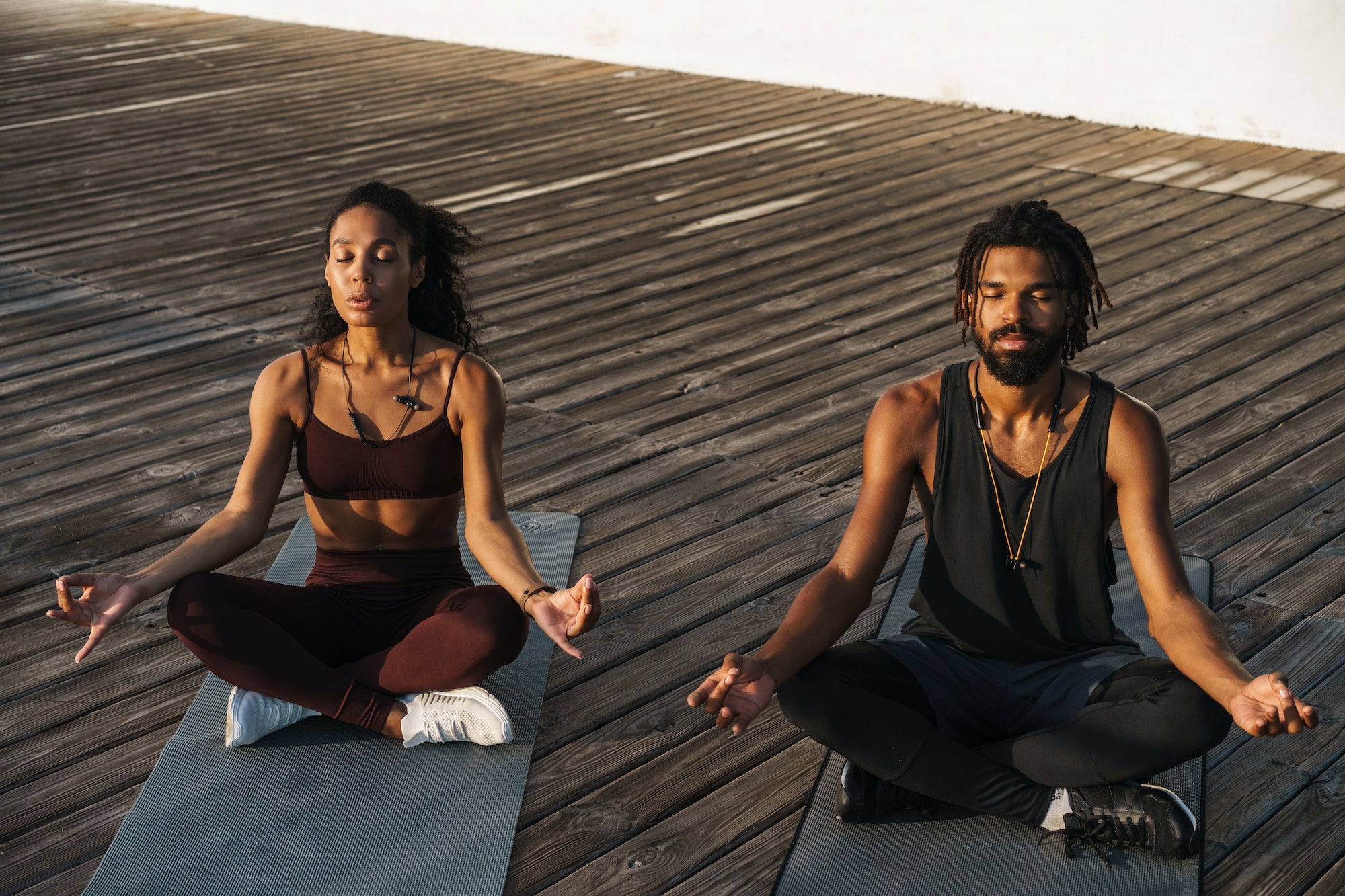 Young happy african american man and woman practicing yoga outdoors