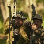 Portrait of a father and son in camouflage hunting with bows and arrows in the woods